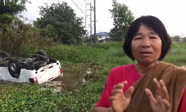 Woman helps driver trapped in half-submerged car in a swamp in Phayao